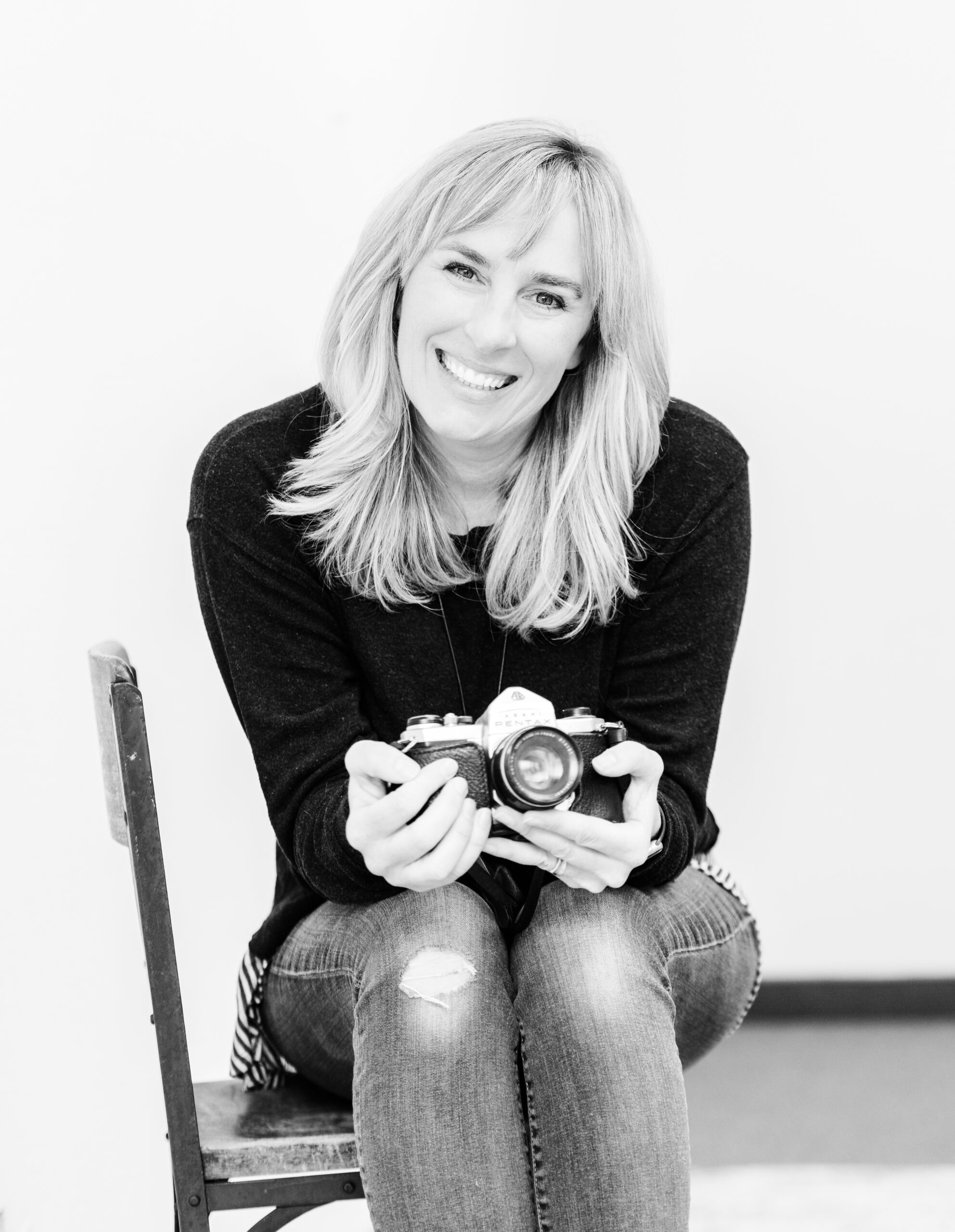 A black and white photograph of Susannah Gill holding a camera.