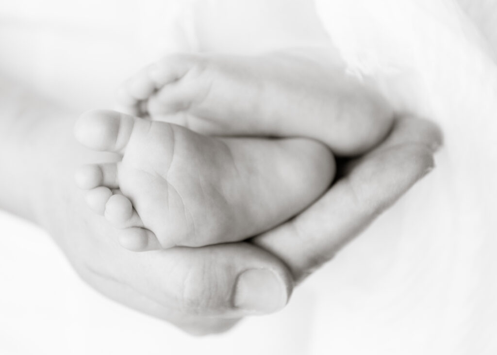 A mother holding a newborn's feet in her hands.