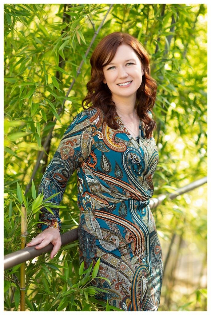 A woman's head shot leaning against her railing with bamboo behind her