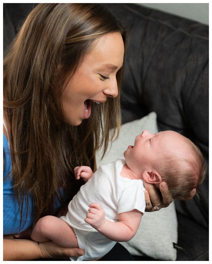 A mom and her newborn baby boy smile at each other.