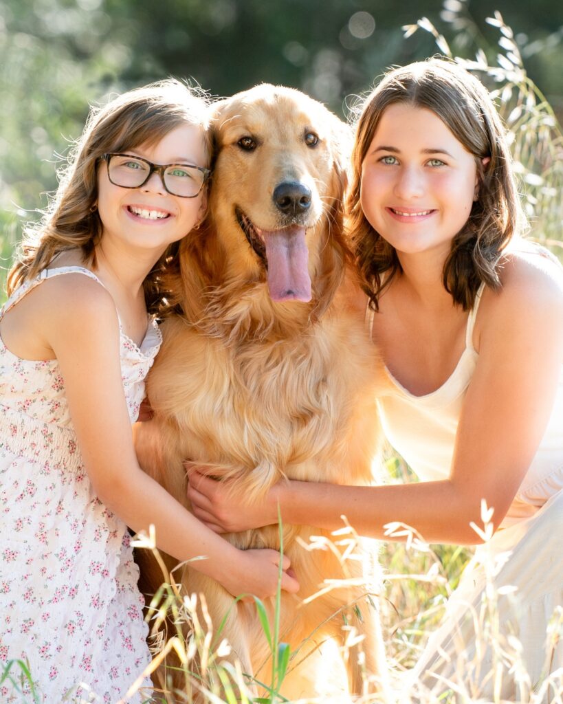 Two sisters with their Golden Retriever hugging
